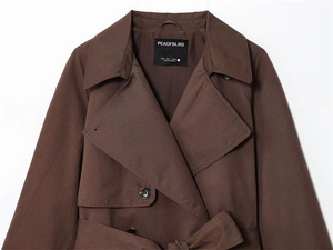 Detail van een donkerbruine trenchcoat met reverskraag en knopen van hars