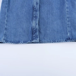 Détail des coutures et texture de l'ourlet sur une jupe en jean bleu délavé
