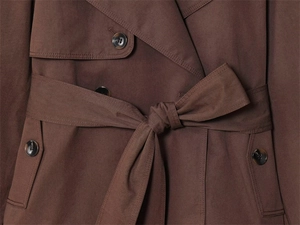 Detail van donkerbruine trenchcoat met ceintuuroptiek en knopen met marmeren textuur