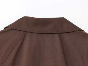 Detail van donkerbruine korte trenchcoat met raglanmouwen en textuur van de kraag