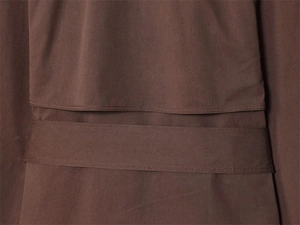 Detail van de taille-stiksels van een donkerbruine trenchcoat met fijne textuur