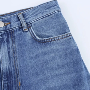 Gros plan détaillé du tissu denim bleu avec coutures orange et détails du bouton en métal