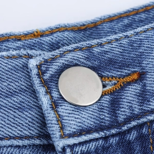 Détail du tissu denim avec coutures orange et bouton argenté de qualité