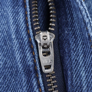 Vue macro du tissu denim bleu foncé avec fermeture éclair YKK et coutures jaunes