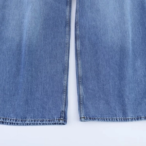 Détail du tissu denim bleu clair avec double couture sur l'ourlet de jambe large