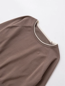 Détail du col en tricot marron moka avec bordure côtelée blanche et coutures ajourées
