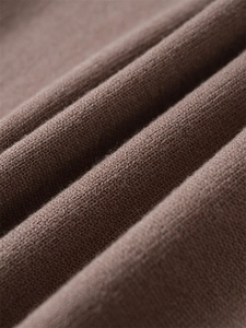 Gros plan détaillé du tissu en maille marron café montrant texture douce et coutures
