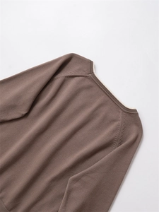 Détail du col d'un pull en maille marron foncé avec doublure intérieure contrastée blanche
