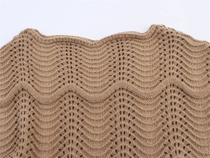 Detailansicht eines braunen Strickkleids mit Wellenmuster und Häkeldetails