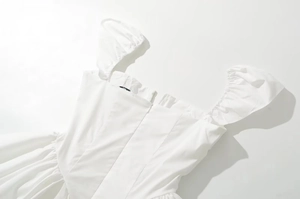 Detail of white square neck dress with puff sleeves and cinched waist corset structure