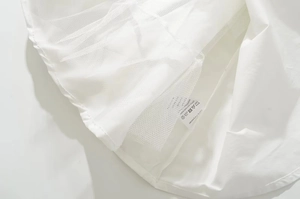 Detail of white dress hem showing polyester fabric texture and mesh tulle lining layer
