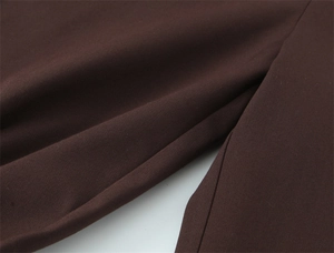 Detailaufnahme der dunkelbraunen Stofftextur und präzisen Nähte der High-Waist-Hose