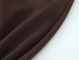 Makroaufnahme der dunkelbraunen Stofftextur und Flachnaht an der hochtaillierten Hose