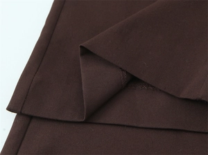 Detailaufnahme der dunkelbraunen Hose mit hoher Taille, Saum und gewebter Stoffstruktur