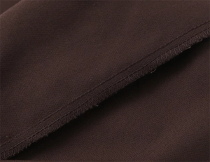 Makroaufnahme der Overlock-Nähte an dunkelbraunen High-Waist-Schlaghosen
