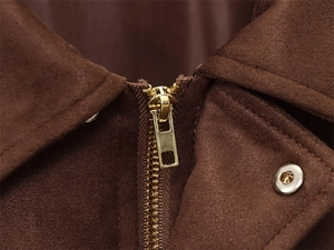 Close-up of golden metal zipper and hardware on dark brown suede jacket fabric