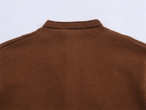 Gros plan sur la maille fine et les coutures d'épaule d'un pull marron à col rond
