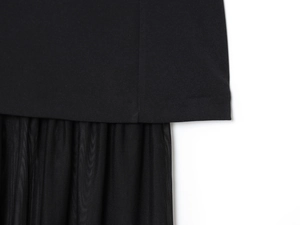 Détail d'une robe noire montrant le contraste du tissu lisse avec la texture en maille