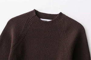 Detailed view of the round neckline and raglan sleeve on this ribbed knit sweater