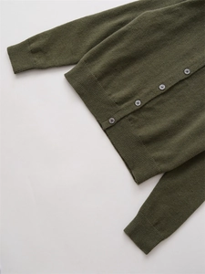 Détail d'un cardigan en laine vert foncé avec poignets côtelés et boutons gris