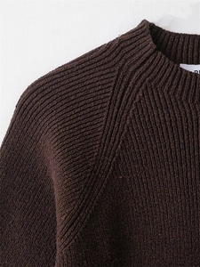 Close-up of dark brown ribbed knit sweater showing the crew neck and raglan sleeve details