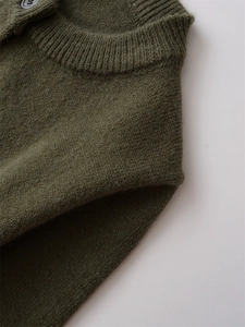 Détail du cardigan en laine vert olive avec col côtelé et bouton gris élégant