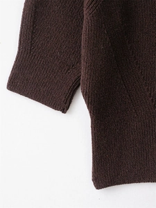Detailed view of the dark brown ribbed knit fabric and cuff texture on this sweater