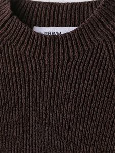 Detail showing the dark brown rib-knit texture and round neckline of the sweater