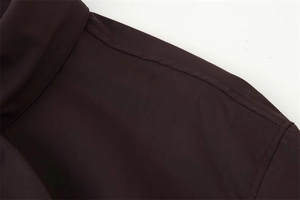 Detailed view of the shoulder stitching on a dark brown poplin fabric shirt for women