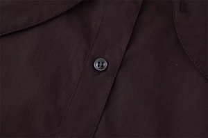 Detail of dark brown poplin shirt showing circular four-hole button and premium stitching