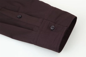 Macro detail of deep brown poplin shirt sleeve with matching resin button closure