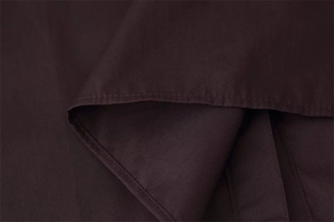 Macro detail of dark brown poplin shirt fabric with neat edge stitching and texture