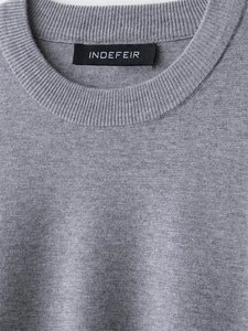 Detailansicht des gerippten Rundhalsausschnitts und der grauen Stricktextur des Pullovers