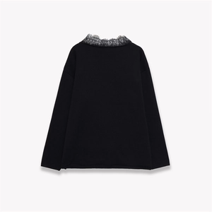 Detail of elegant black knit top featuring intricate lace neckline and long sleeves