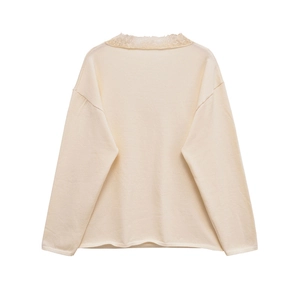 Detail of elegant beige knitted top featuring intricate lace trim on the collar and hem