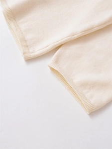 Detailed macro view of the soft cream lace knit fabric and elastic ribbed sleeve cuff