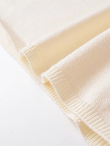 Close-up detail of cream knitted sweater hem with premium ribbed cuffs and soft texture
