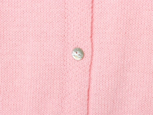 Dettaglio macro del morbido tessuto in maglia mohair rosa e bottone perlato raffinato