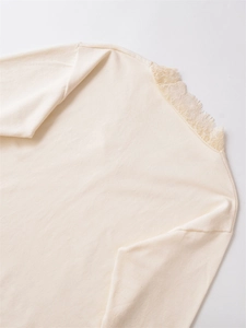 Detail of cream polyester blend knit top showing delicate lace trim on the neckline