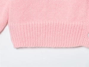Dettaglio del cardigan rosa in maglia con texture mohair e un bottone di perla