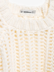 Detail des Rundhalsausschnitts eines grob gestrickten Pullovers in Cremeweiß mit Textur