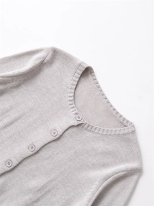Dettaglio cardigan in maglia grigio chiaro con scollo rotondo e chiusura a bottoni