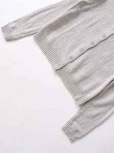 Dettaglio del cardigan in maglia grigio chiaro con polsini a coste e bottoni tondi