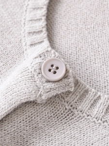 Dettaglio del bottone opaco e della morbida trama a maglia di un cardigan donna