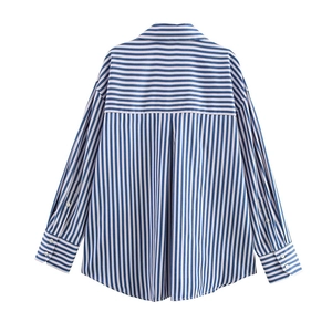 Detail view of the back of a blue striped poplin shirt with pleats and drop shoulder