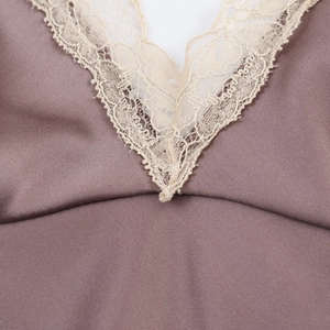 Détail du col en V avec bordure en dentelle beige sur une robe midi en satin rose