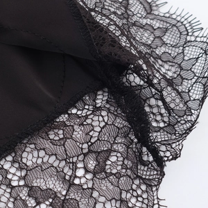 Close-up of black satin midi skirt featuring delicate eyelash lace trim and stitching