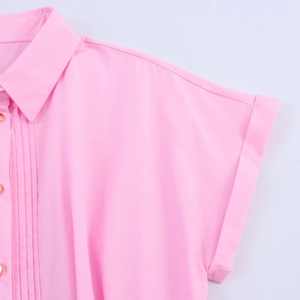 Dettaglio dell'abito midi in popeline rosa con bottoni dorati e trama a pieghe eleganti