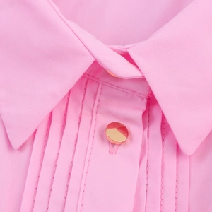 Dettaglio dell'abito midi rosa con pieghe verticali e bottone in metallo dorato