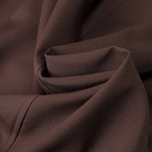 Gros plan du tissu marron foncé avec texture fine et détails de couture élégants